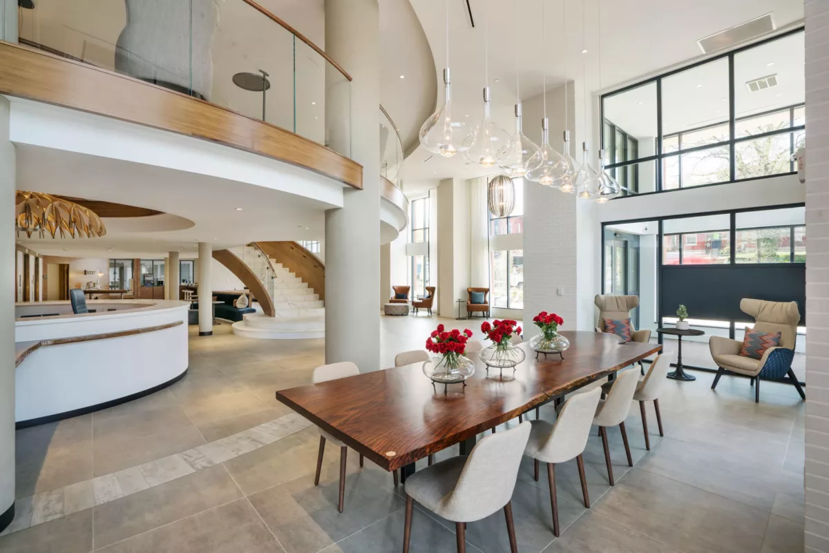 Communal dining table in open lounge with high ceilings and natural light.