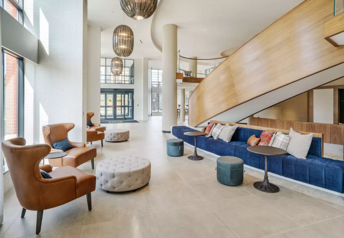 Casual seating area with sofas, ottomans, and tall windows.