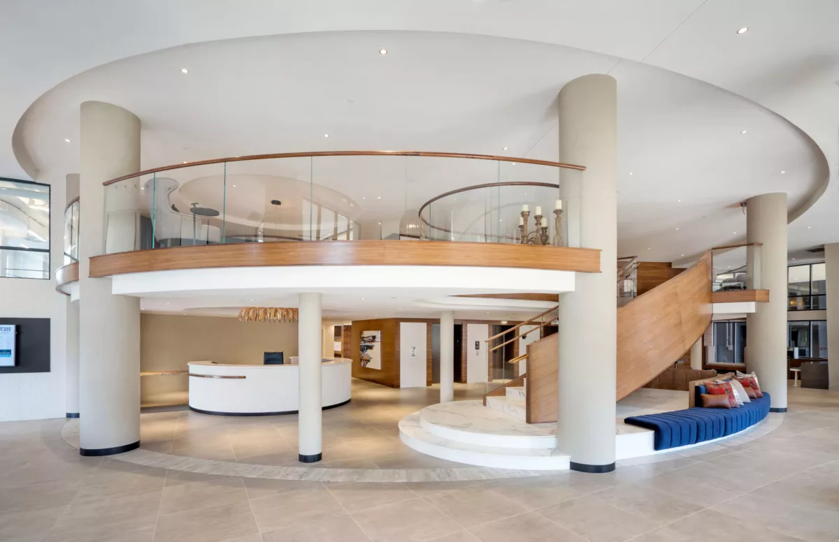 Lobby view highlighting circular desk, wood accents, and upper-level balcony.