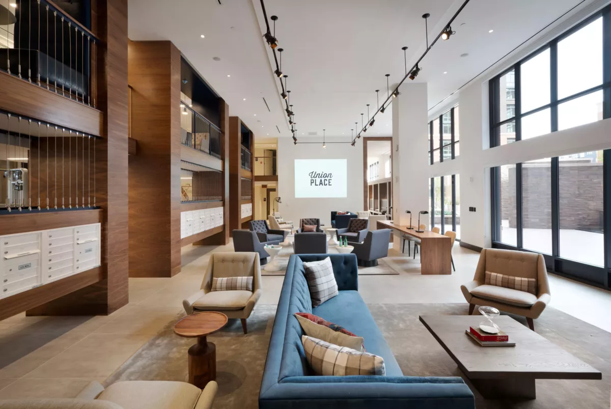 Spacious lounge with blue sofas, wood shelving, and track lighting.