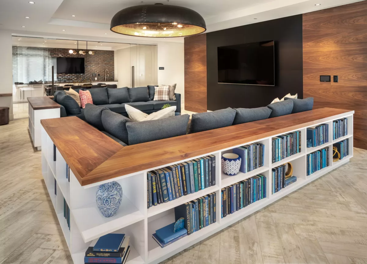 Resident lounge with sectional seating, wall-mounted TV, and built-in shelving.