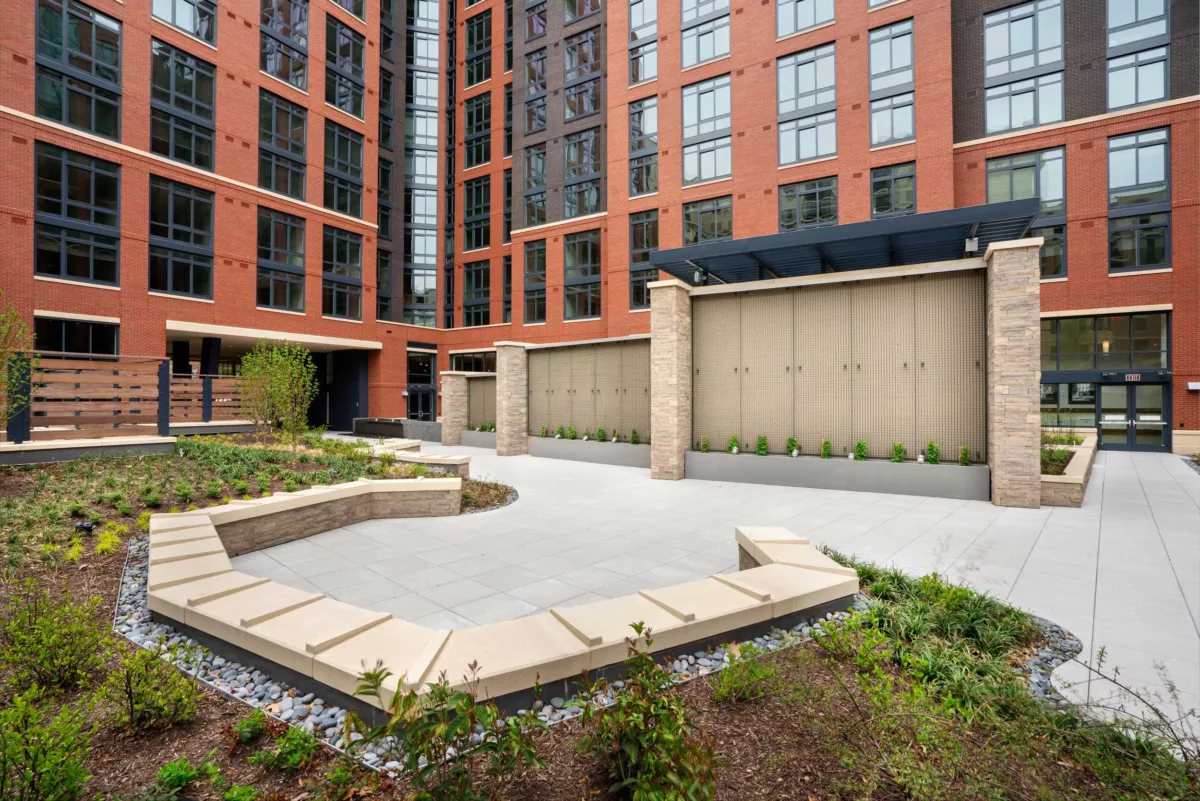 Outdoor courtyard area with seating walls, landscaped beds, and surrounding apartments.