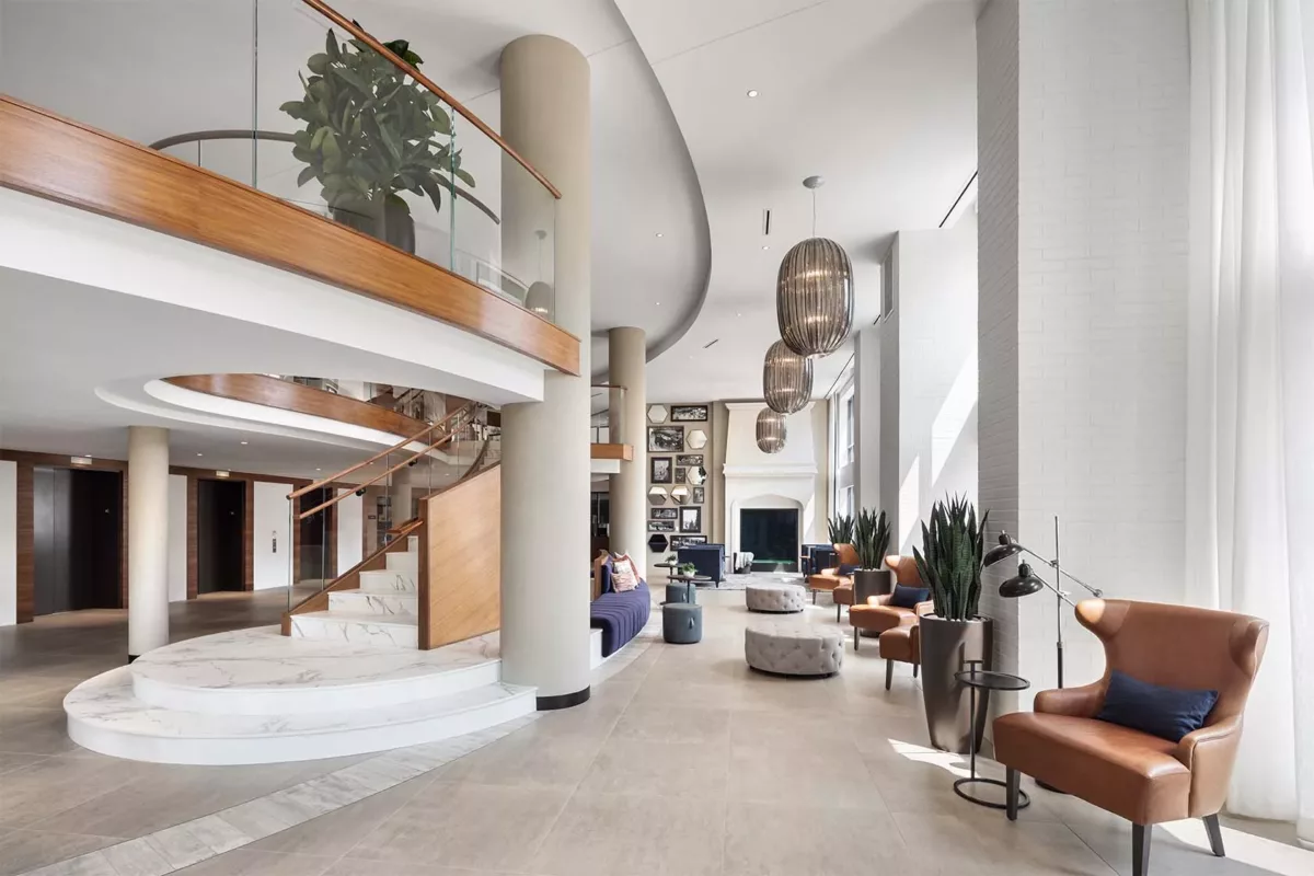 Lounge seating beneath curved staircase with modern furniture and plants.