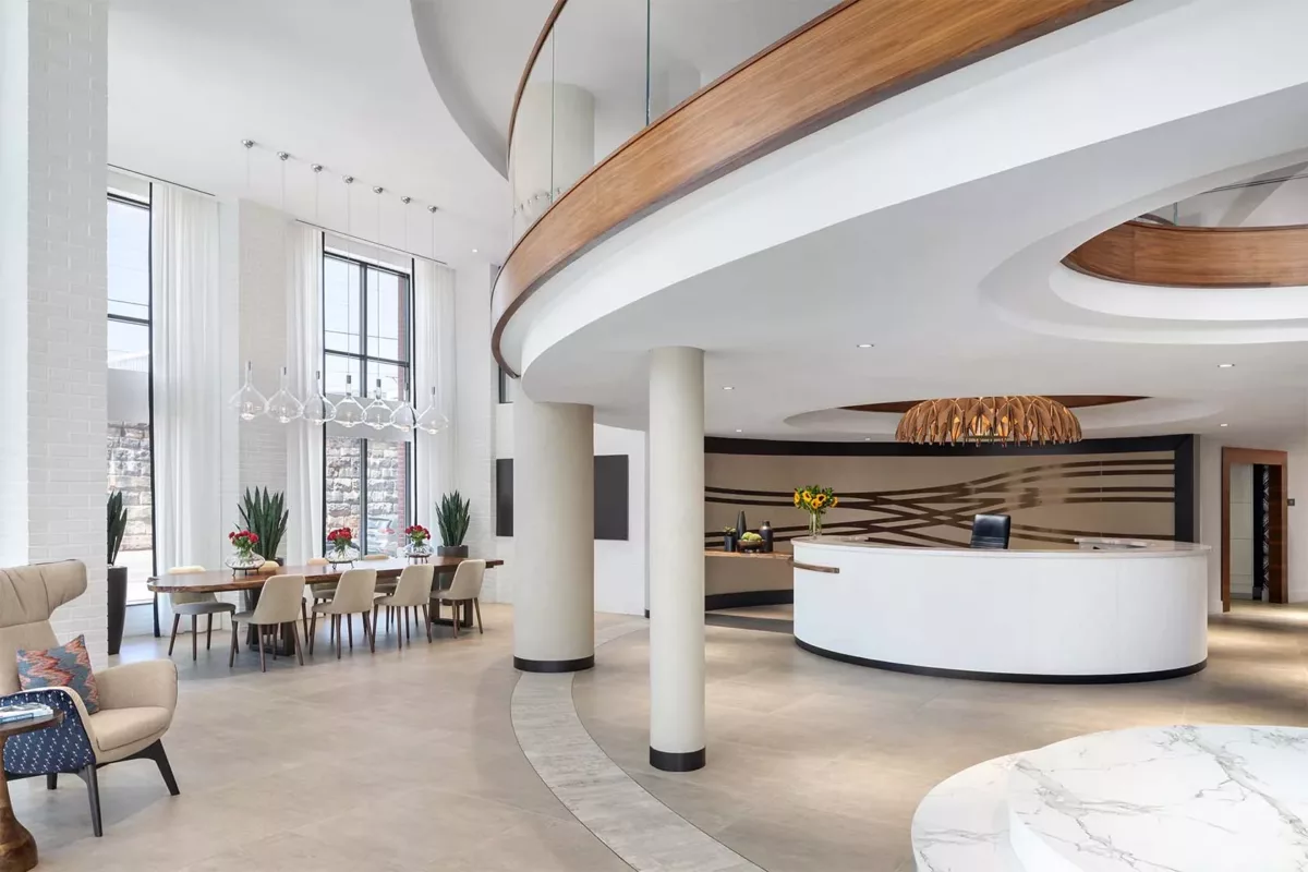 Open lobby with curved mezzanine, white columns, and modern reception desk.