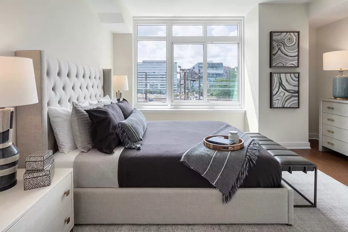 Bedroom with large window, neutral bedding, and minimal modern décor.