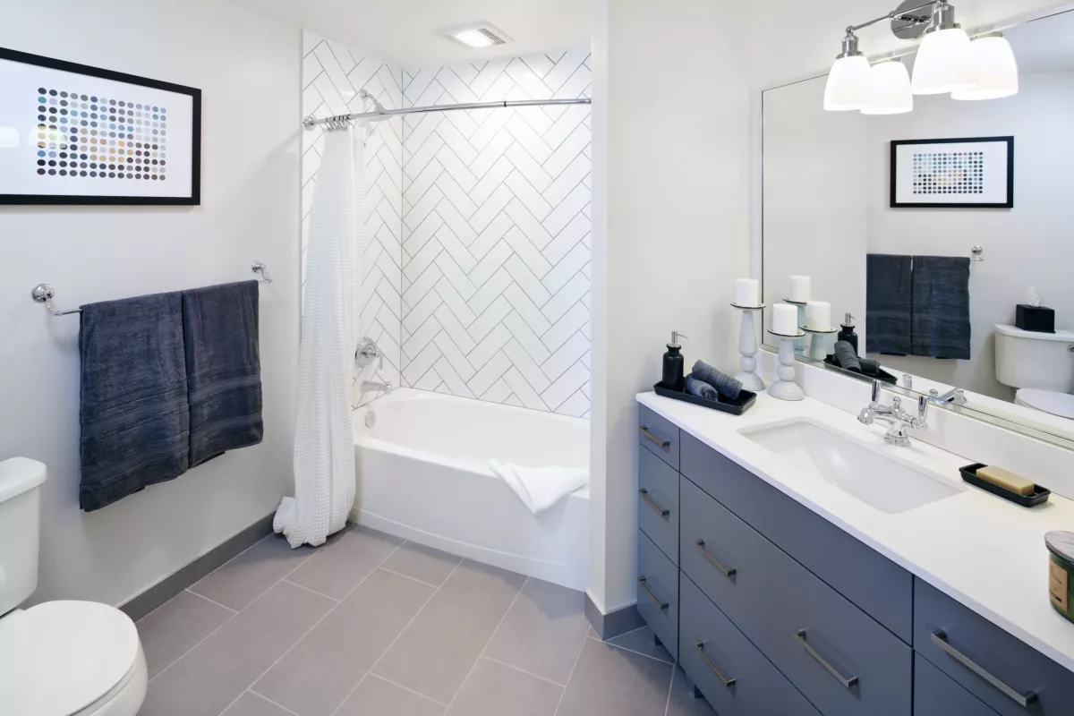 Bathroom with tub-shower combo, tiled walls, and vanity with storage.