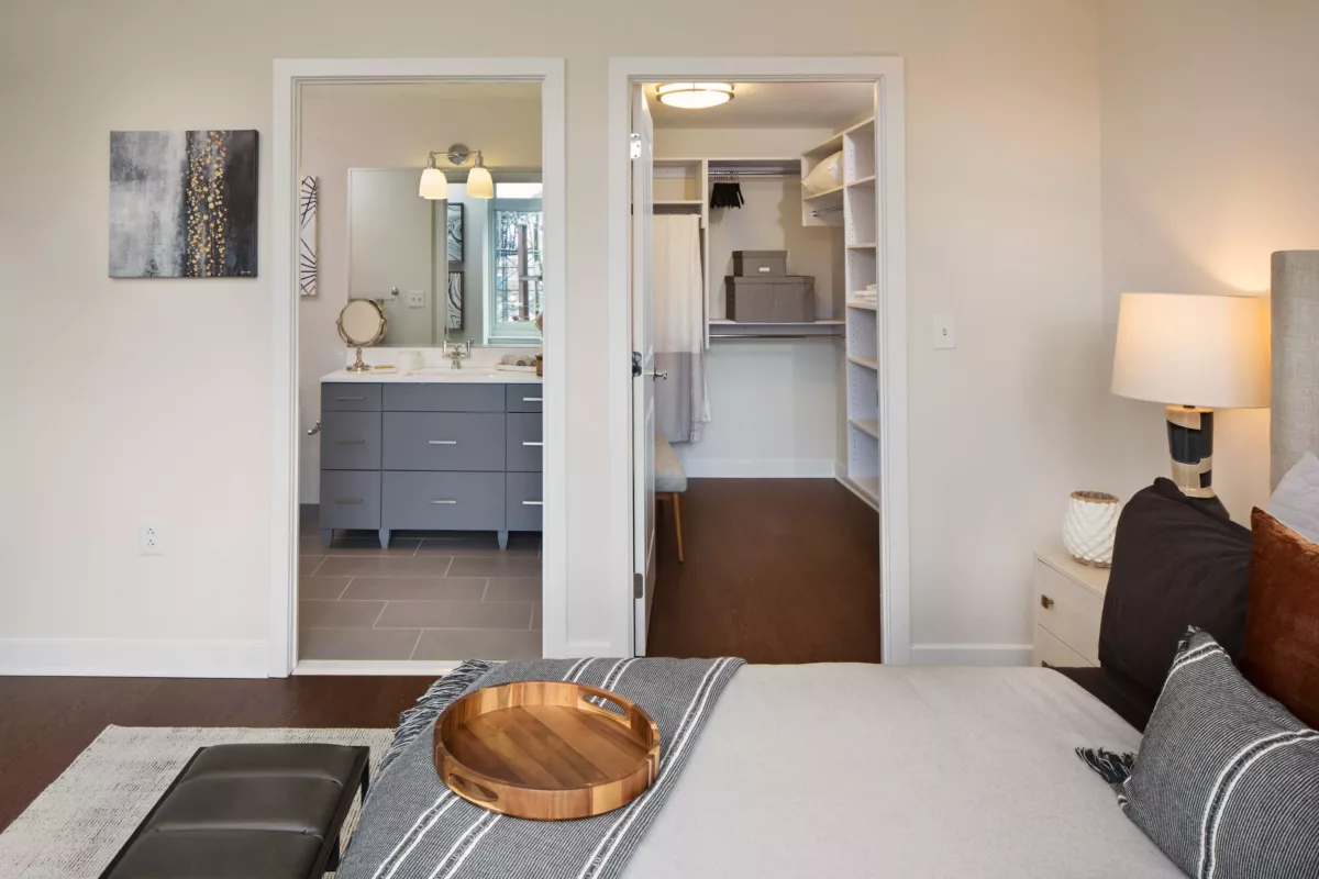 Bedroom view toward bathroom with wood floors and compact vanity.