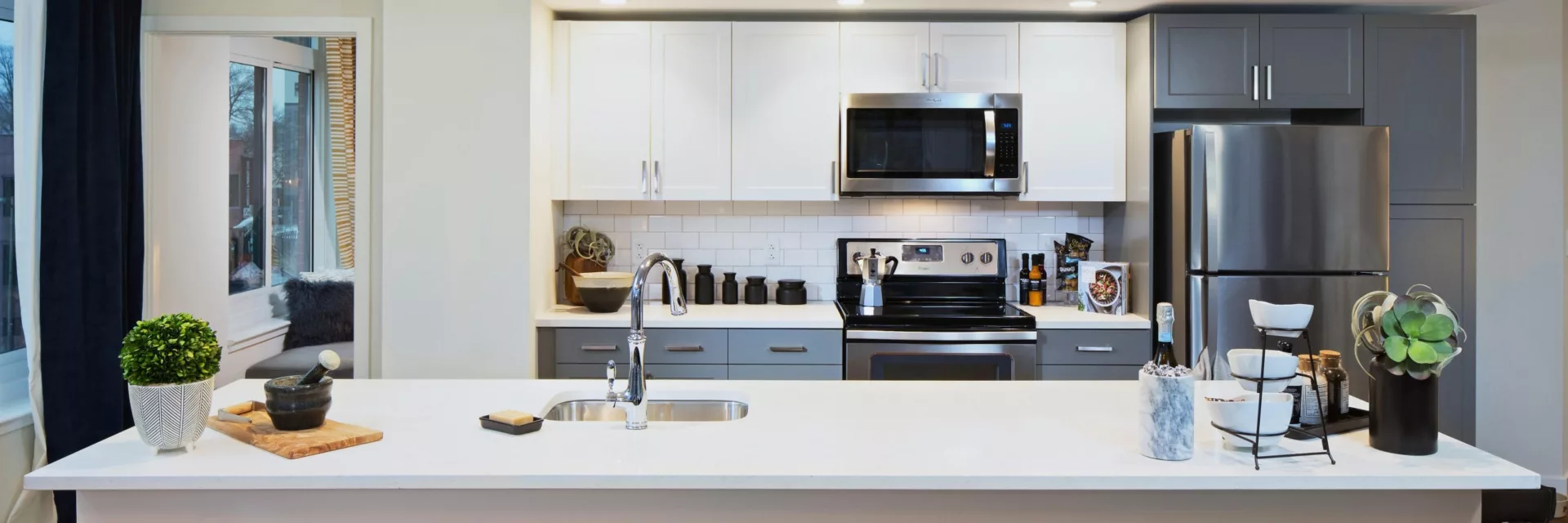 Kitchen at Union Place with island; gray/white cabinets; white countertops; and stainless steel appliances
