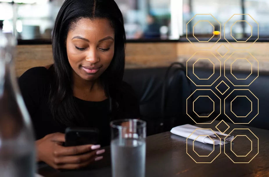 woman sitting at a table in a cafe looking at her mobile phone